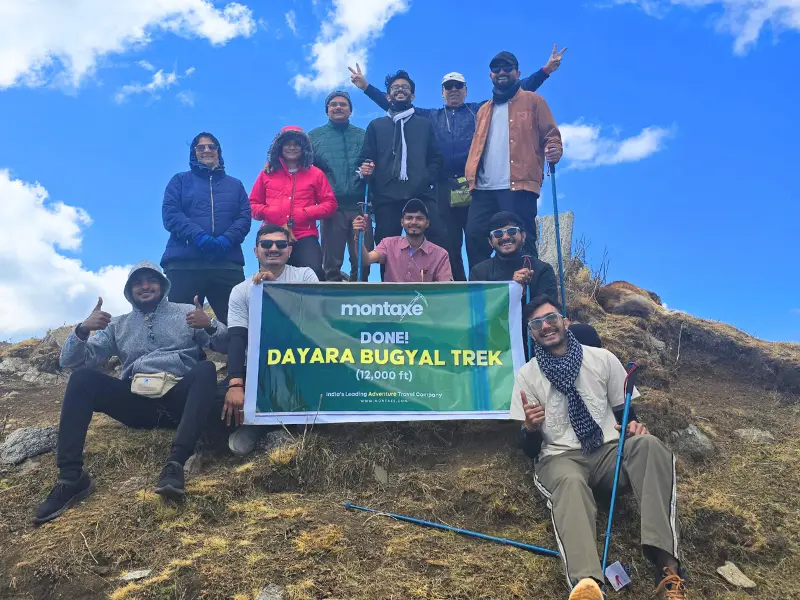 Best Winter Treks In Uttarakhand 3 Trekkers completing Dayara Bugyal trek with snow-covered Himalayan peaks in the background