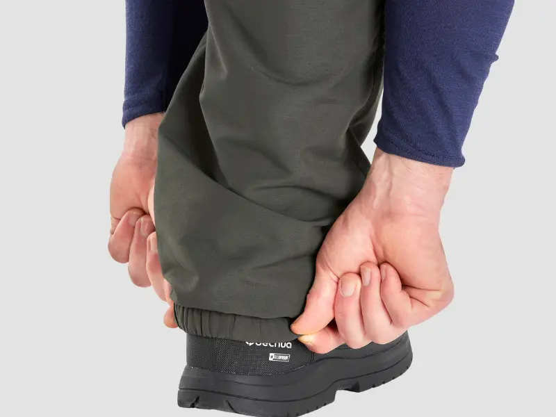 Decathlon SH100 Warm Water-Repellent Hiking Trousers Review: Honest Choice for Winter Treks? 3 Hiker adjusting the elastic ankle cuff of Decathlon SH100 trousers to prevent snow entry.